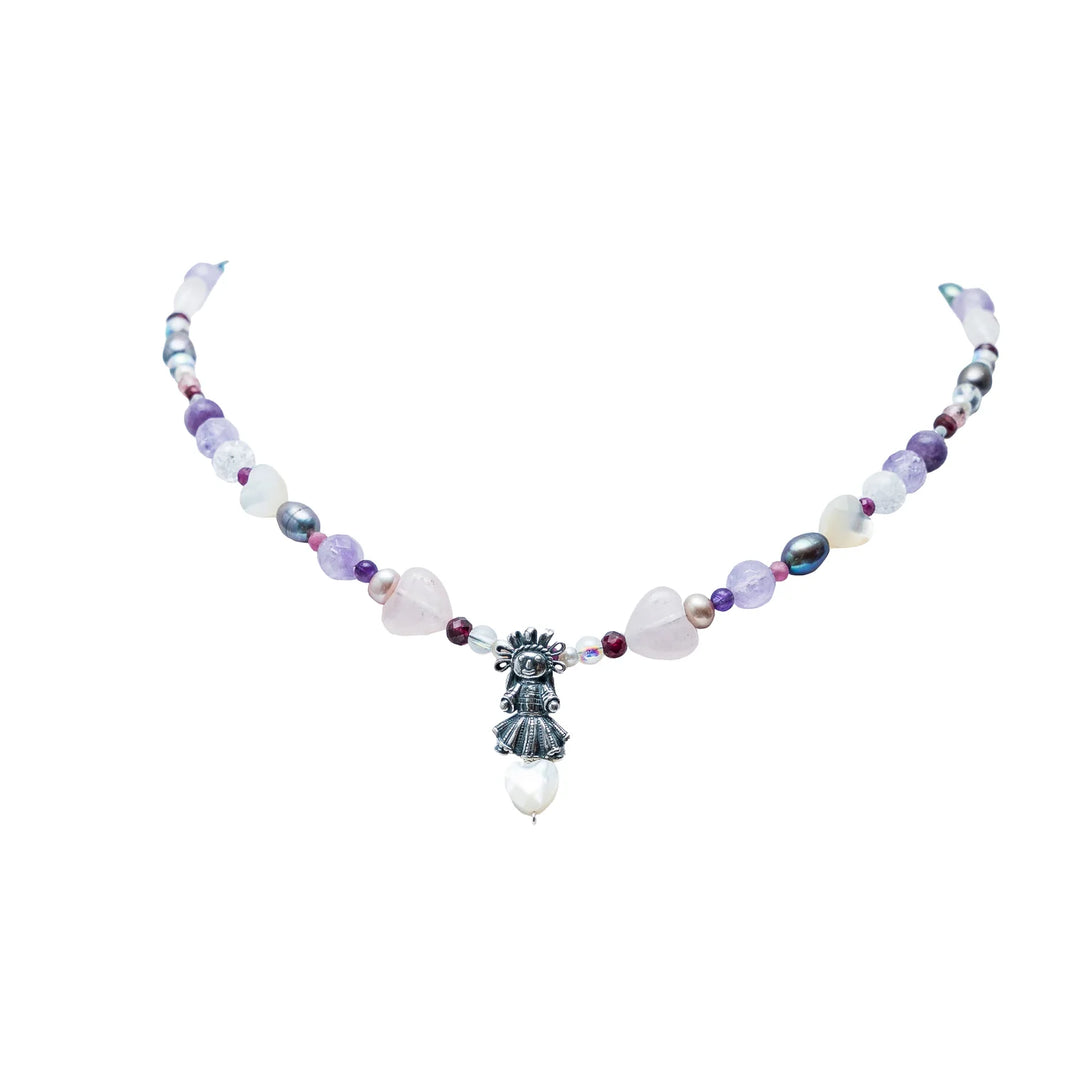Handmade Muñeca Mexicana gemstone necklace with purple beads, heart accents, pearls, and silver doll charm on white background