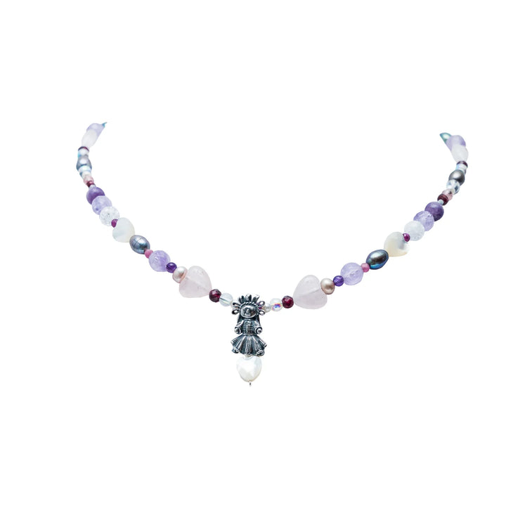 Handmade Muñeca Mexicana gemstone necklace with purple beads, heart accents, pearls, and silver doll charm on white background