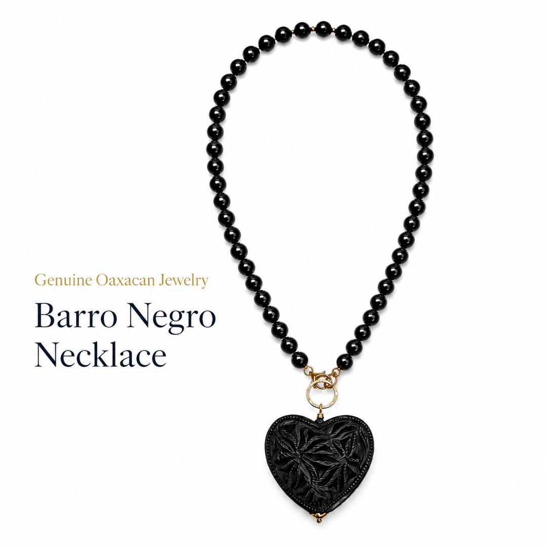 Handmade Barro Negro heart necklace photographed on clean white background, authentic black clay Mexican jewelry by Bootsologie featuring carved sacred heart pendant and glossy black beads.
