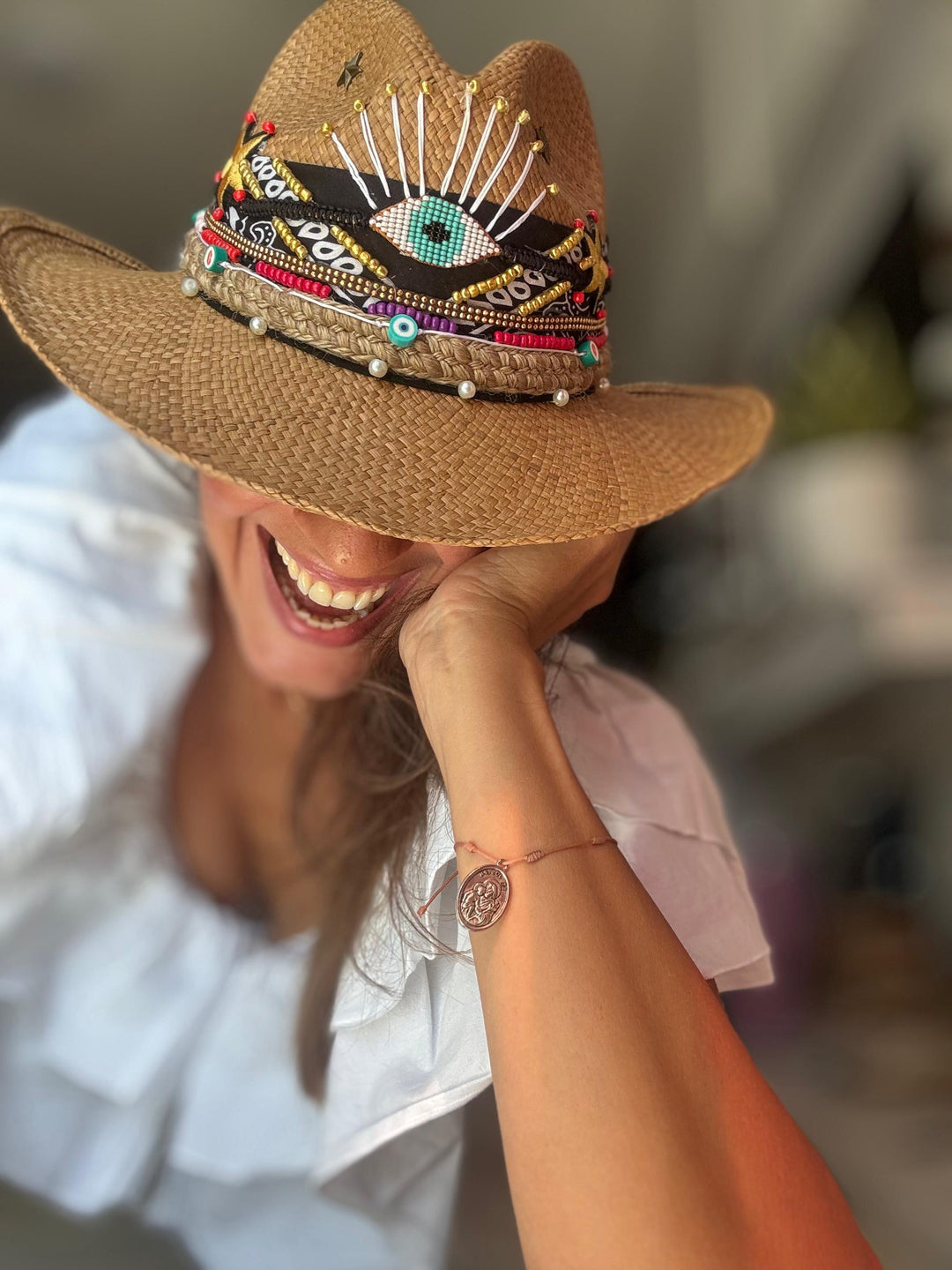 Woman wearing handmade Colombian evil eye straw hat styled with luxury resort wear and boho beach fashion
