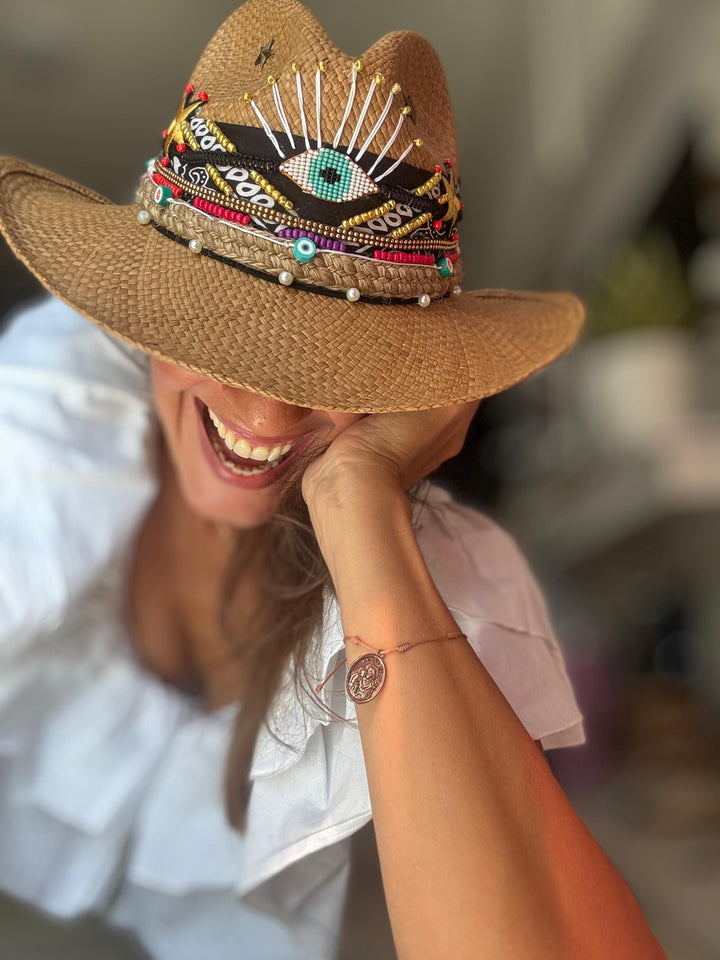 Woman wearing handmade Colombian evil eye straw hat styled with luxury resort wear and boho beach fashion