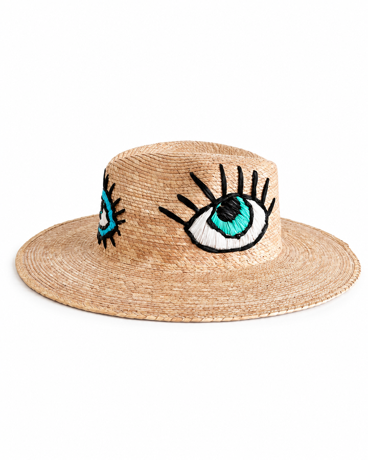 Side view of handmade straw hat with blue embroidered eye design on crown