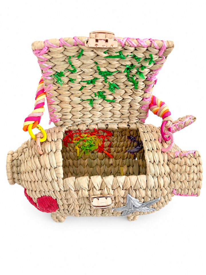 Open pig straw clutch showing interior woven construction, flap closure, and handmade bag details.