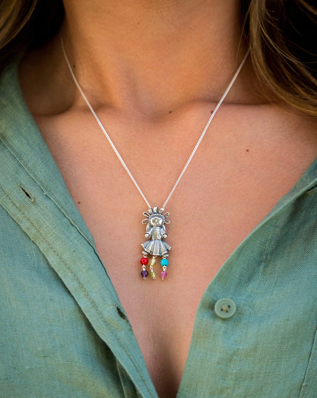 Close-up of Muñeca Mexicana sterling silver pendant and natural gemstones
