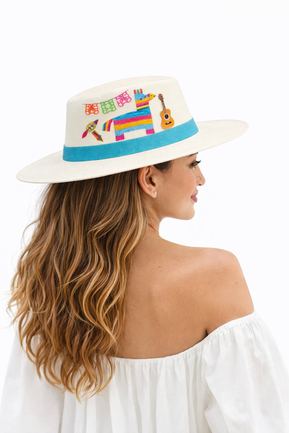 Model wearing a hand painted Mexican Fiesta wide brim hat with colorful piñata and papel picado artwork, styled as a bold artisan statement hat by Bootsologie