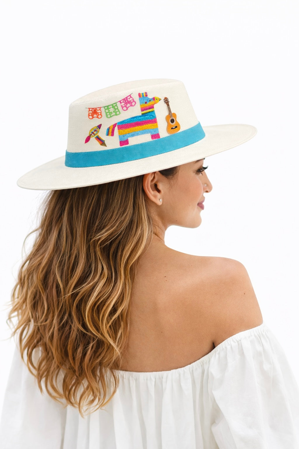 Model wearing a hand painted Mexican Fiesta wide brim hat with colorful piñata and papel picado artwork, styled as a bold artisan statement hat by Bootsologie