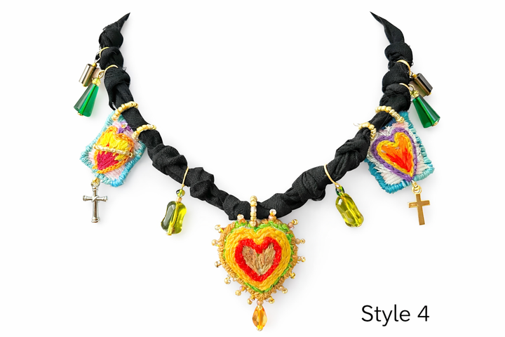 Close up of Sacred Heart Milagro pendant with embroidery, beads, charms, and textile details