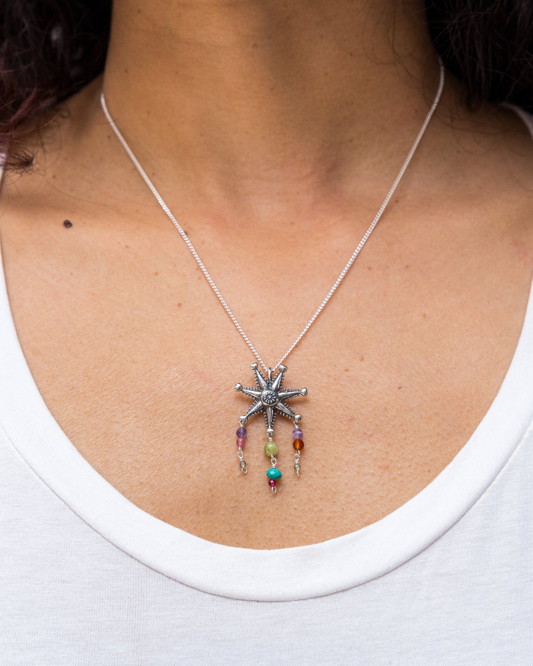 Close-up of silver piñata pendant necklace with purple turquoise green amber and red gemstone drops