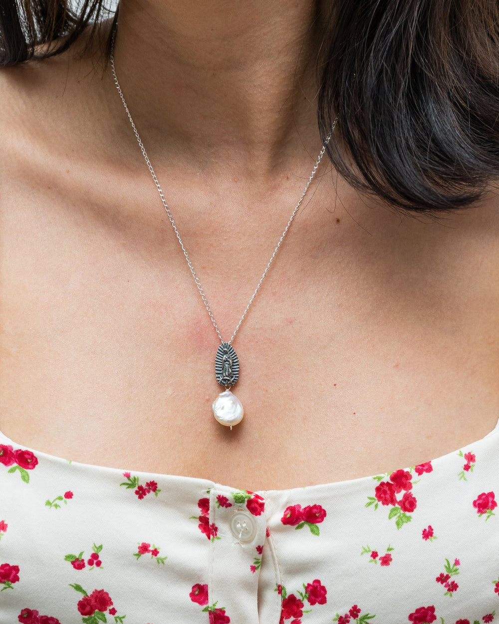 Close-up of Virgen de Guadalupe silver pendant with pearl drop accent