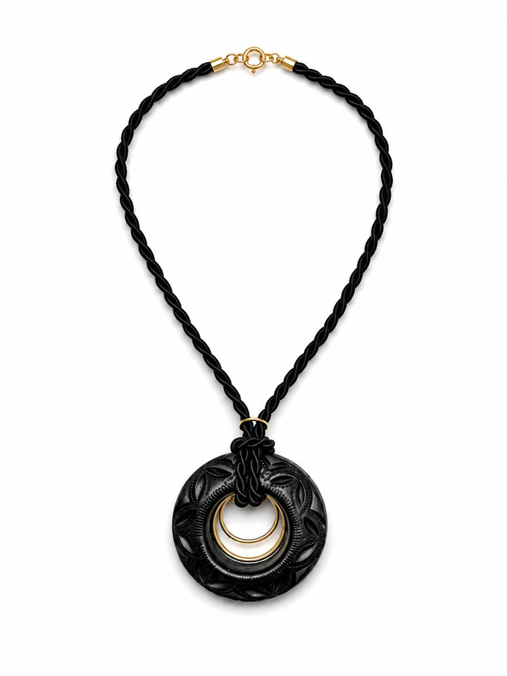 Handmade Barro Negro statement necklace on white background featuring hand carved black clay pendant with double gold rings and twisted black cord by Bootsologie