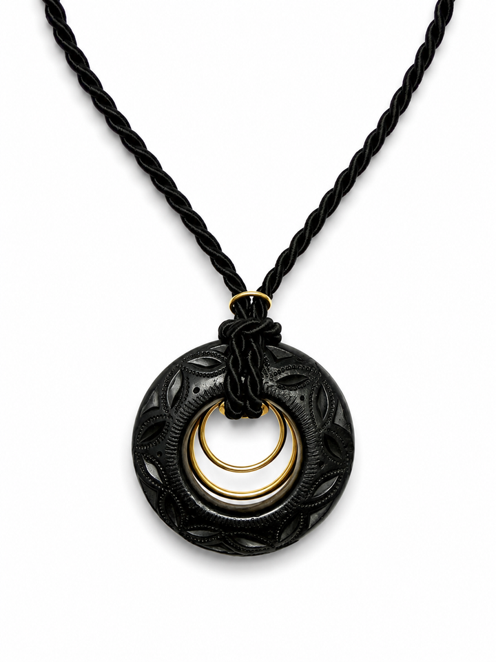 Close-up of authentic Oaxaca Barro Negro necklace showcasing intricate hand carved black clay texture and artisan gold ring detail on white background