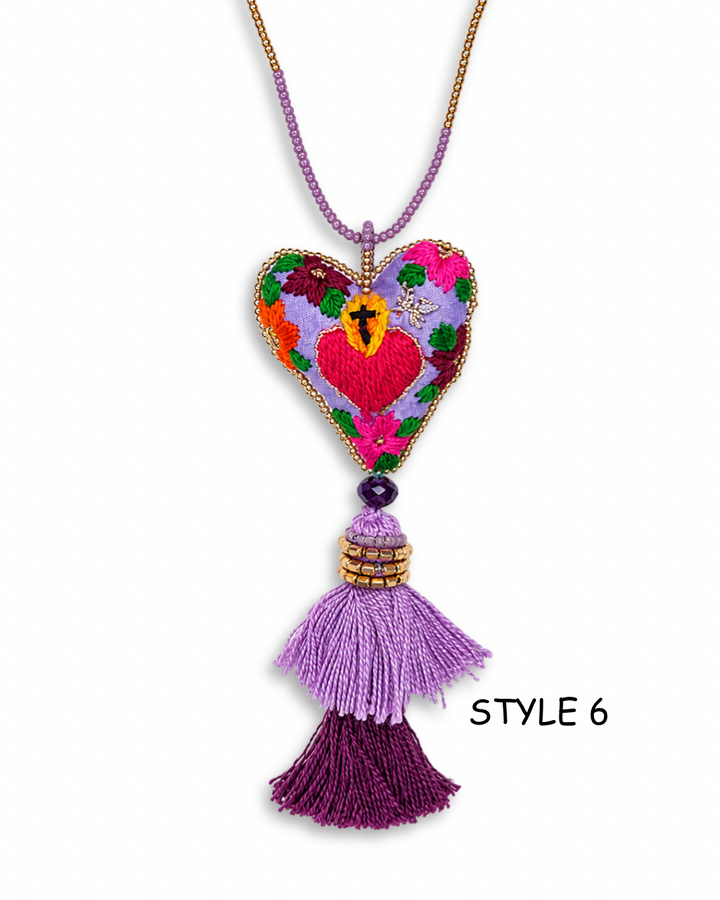 Artisan Mexican folk art necklace with floral sacred heart embroidery and red crystal tassels on white background