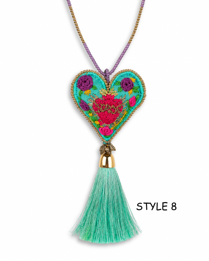 Collection of handmade embroidered sacred heart necklaces in colorful boho Mexican folk art styles on white background