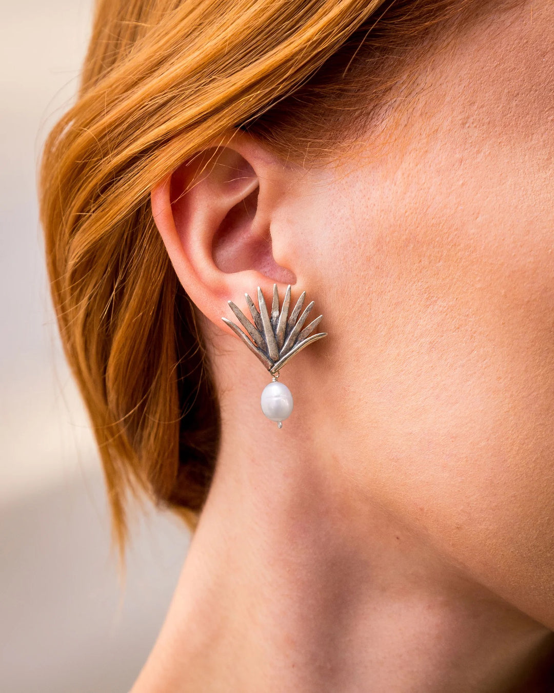 Woman wearing Mexican silver agave earrings with pearl drops by Bootsologie