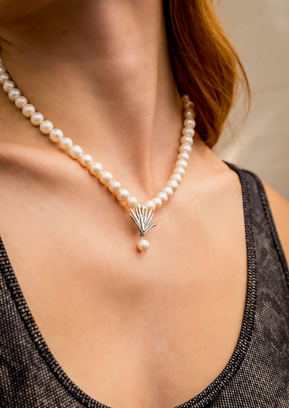 Woman wearing pearl necklace with Mexican silver agave pendant and black top