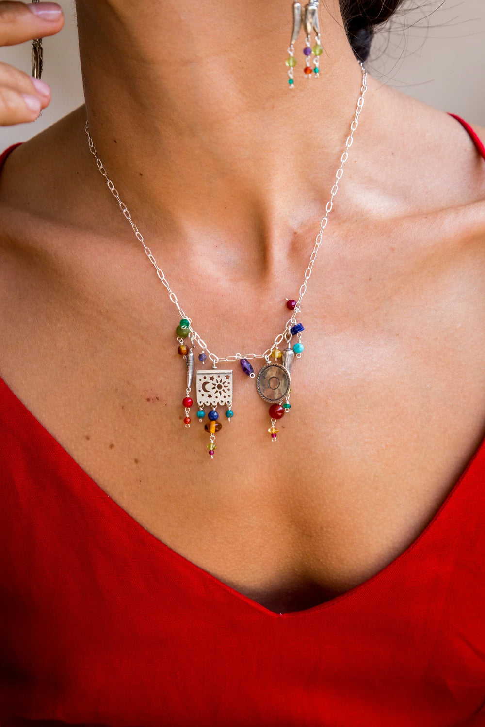 Woman wearing colorful Mexican silver fiesta necklace with papel picado sombrero and chile charms