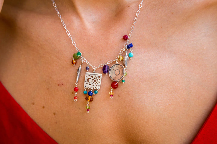 Close-up of Mexican silver charm necklace with papel picado sombrero chile peppers and multicolor gemstone accents