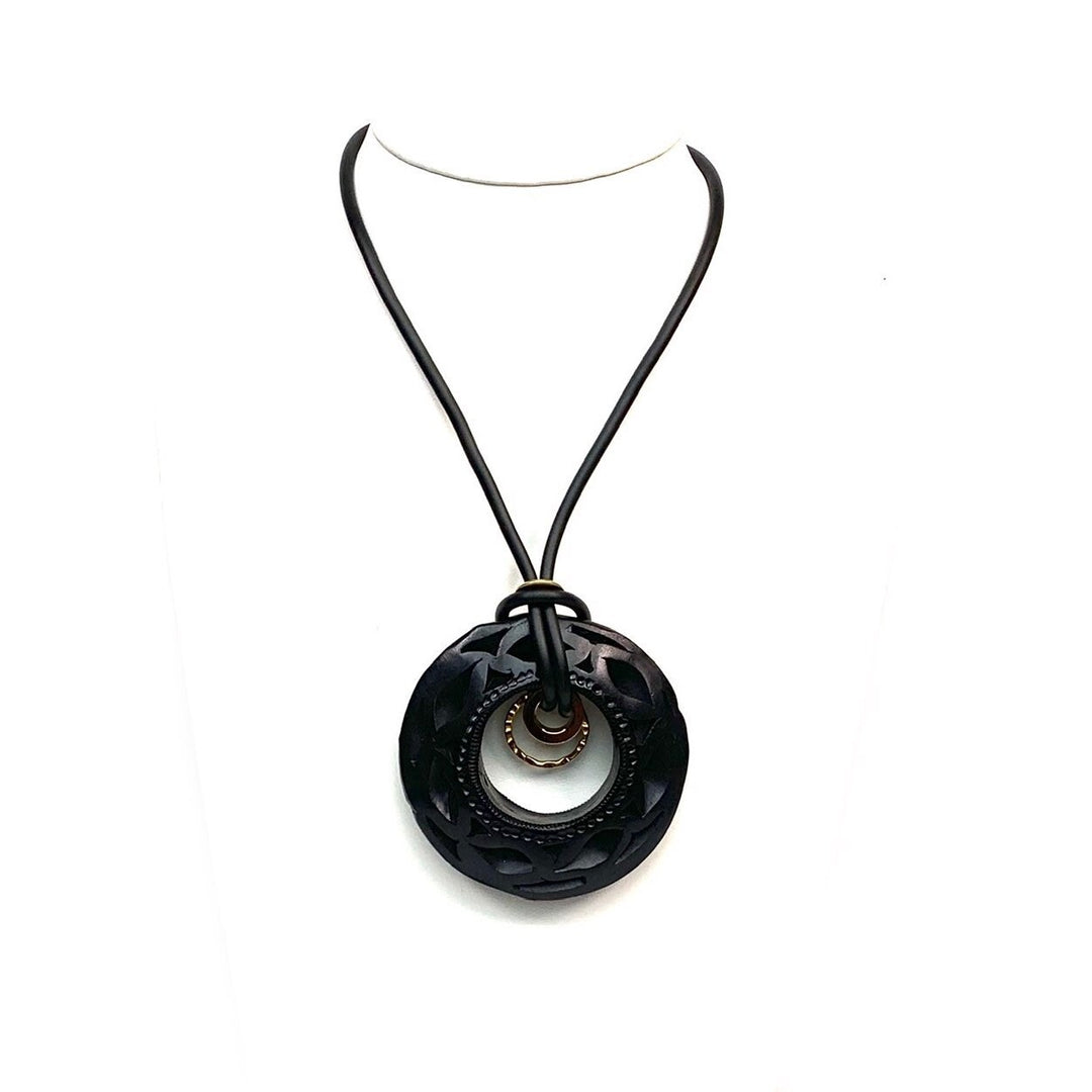 Close-up of authentic Oaxaca Barro Negro necklace showcasing intricate hand carved black clay texture and artisan gold ring detail on white background