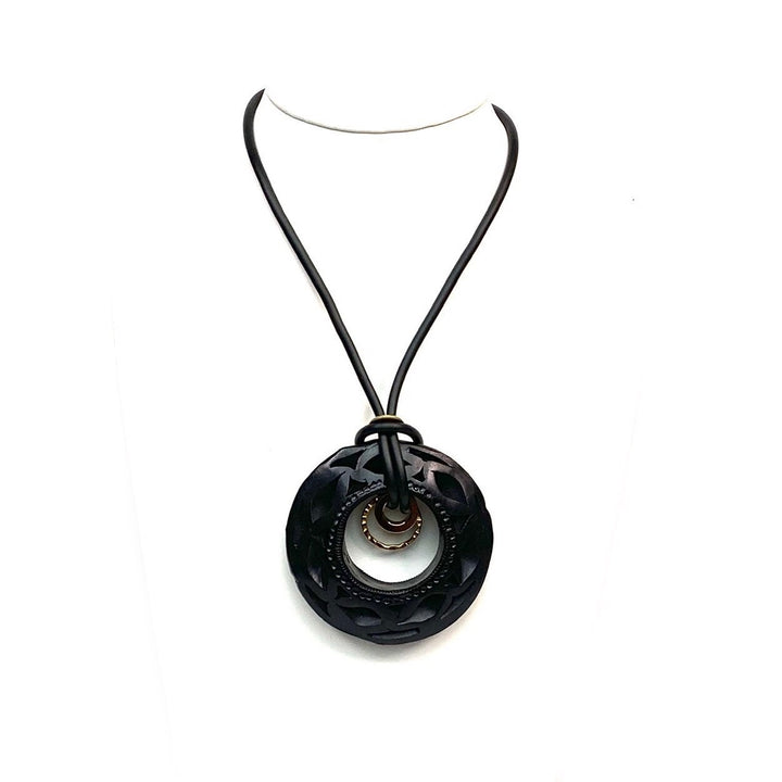 Close-up of authentic Oaxaca Barro Negro necklace showcasing intricate hand carved black clay texture and artisan gold ring detail on white background