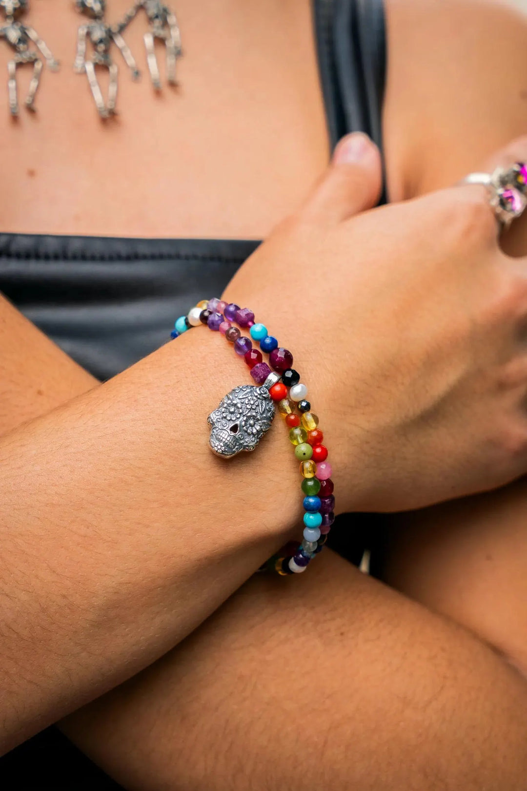 Woman wearing Mexican Catrina charm bracelet with jade gemstone accents by Bootsologie