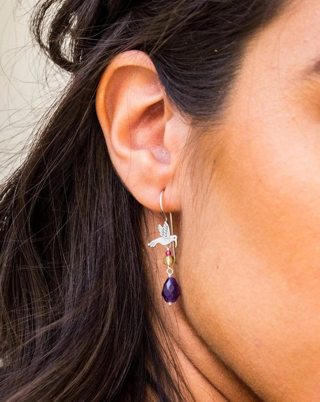 Close-up of Mexican silver hummingbird earrings with colorful gemstone dangle details
