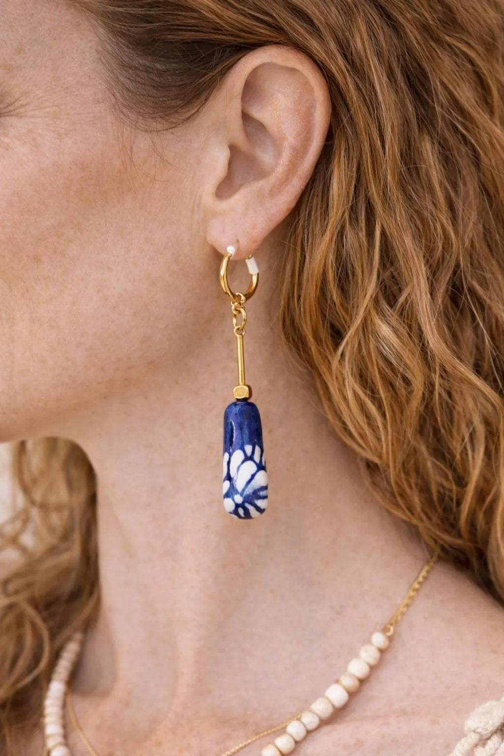 Close up of hand-painted Mexican Talavera ceramic earrings with cobalt blue floral design and gold plated brass hardware