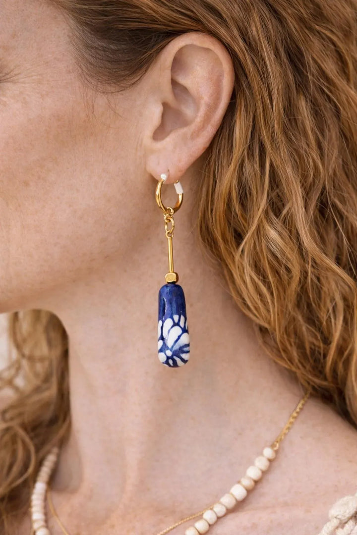 Close up of hand-painted Mexican Talavera ceramic earrings with cobalt blue floral design and gold plated brass hardware