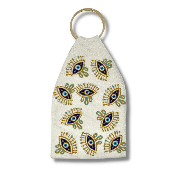 Handmade Colombian Wayuu evil eye clutch with colorful punch needle eye motif and gold ring handles on white background.