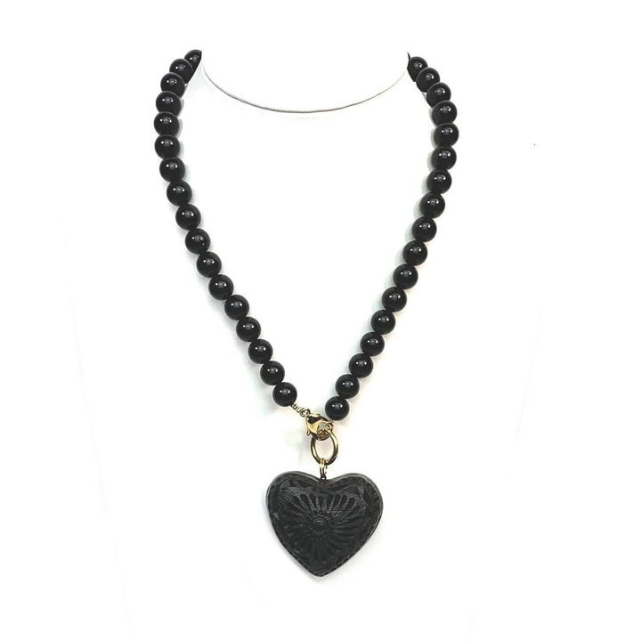 Black sacred heart necklace handcrafted in Oaxaca, Mexico displayed on pure white background with glossy black beads and artisan carved clay pendant by Bootsologie.